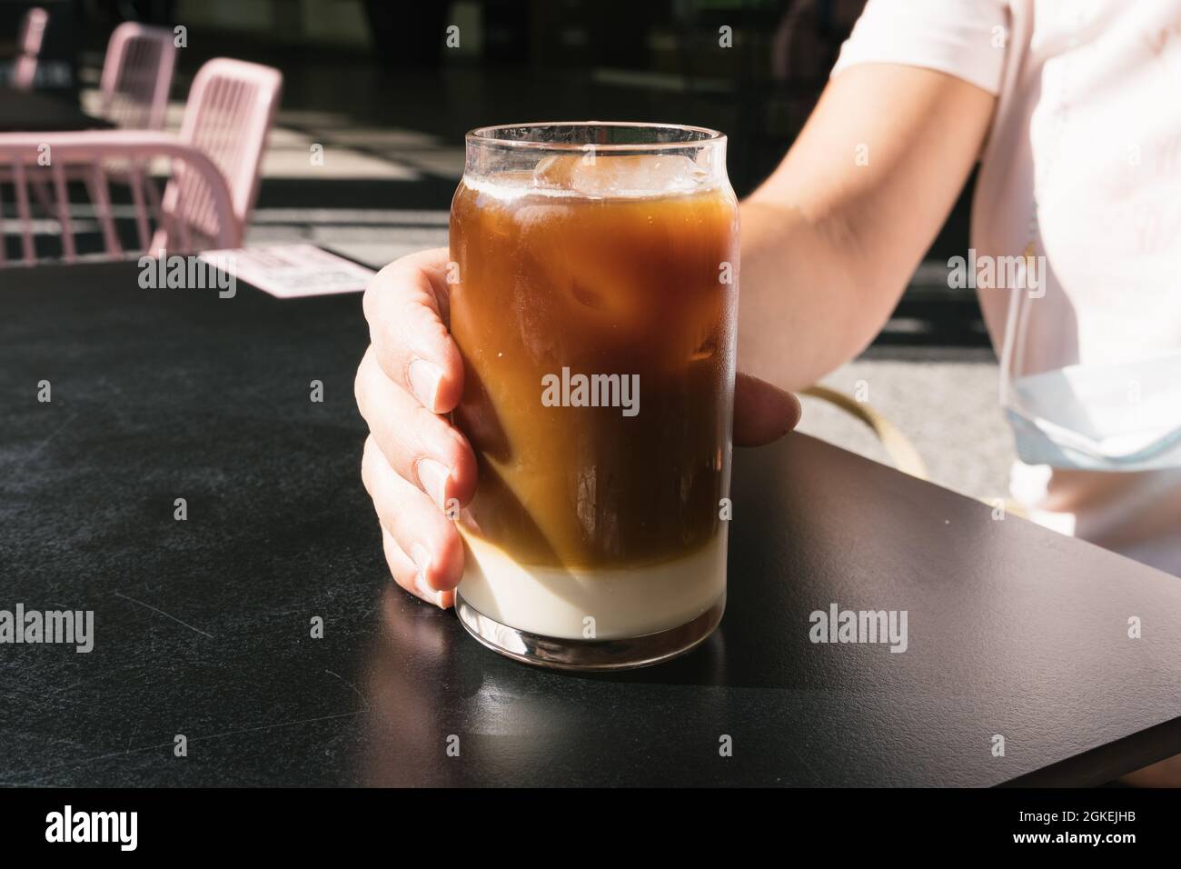 Donna che tiene un gustoso bicchiere di caffè freddo con latte. Foto Stock