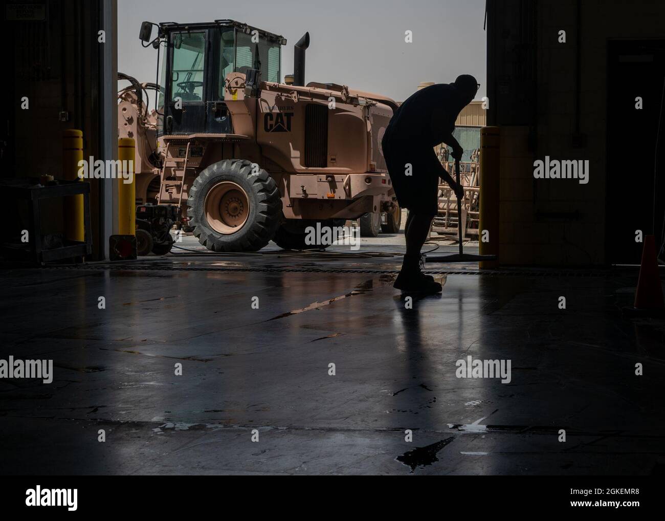 U.S. Air Force staff Sgt. Tristan Davis, 379th Expeditionary Logistics Readiness Squadron il manutentore dell'apparecchiatura di movimentazione del materiale, usa un spatola per pulire il pavimento del negozio dopo una riparazione completata, 31 marzo 2021, alla base aerea di al Udeid, Qatar. Il mantenimento di un ambiente di lavoro pulito evita gli incidenti di sicurezza causati da un pavimento bagnato o scivoloso. Foto Stock