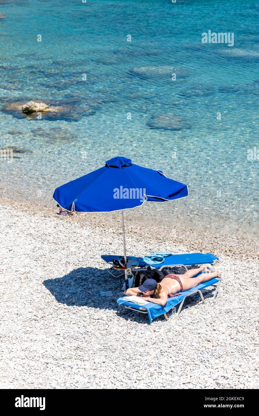 Turista sdraiato su un lettino sulla spiaggia, Rodi, Dodecaneso, Grecia Foto Stock