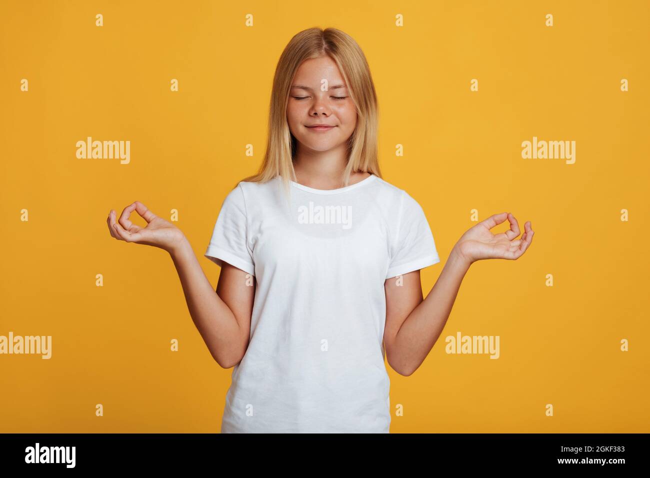 Ragazza bionda soddisfatta adolescente in t-shirt bianca con occhi chiusi prendere pausa, meditazione Foto Stock