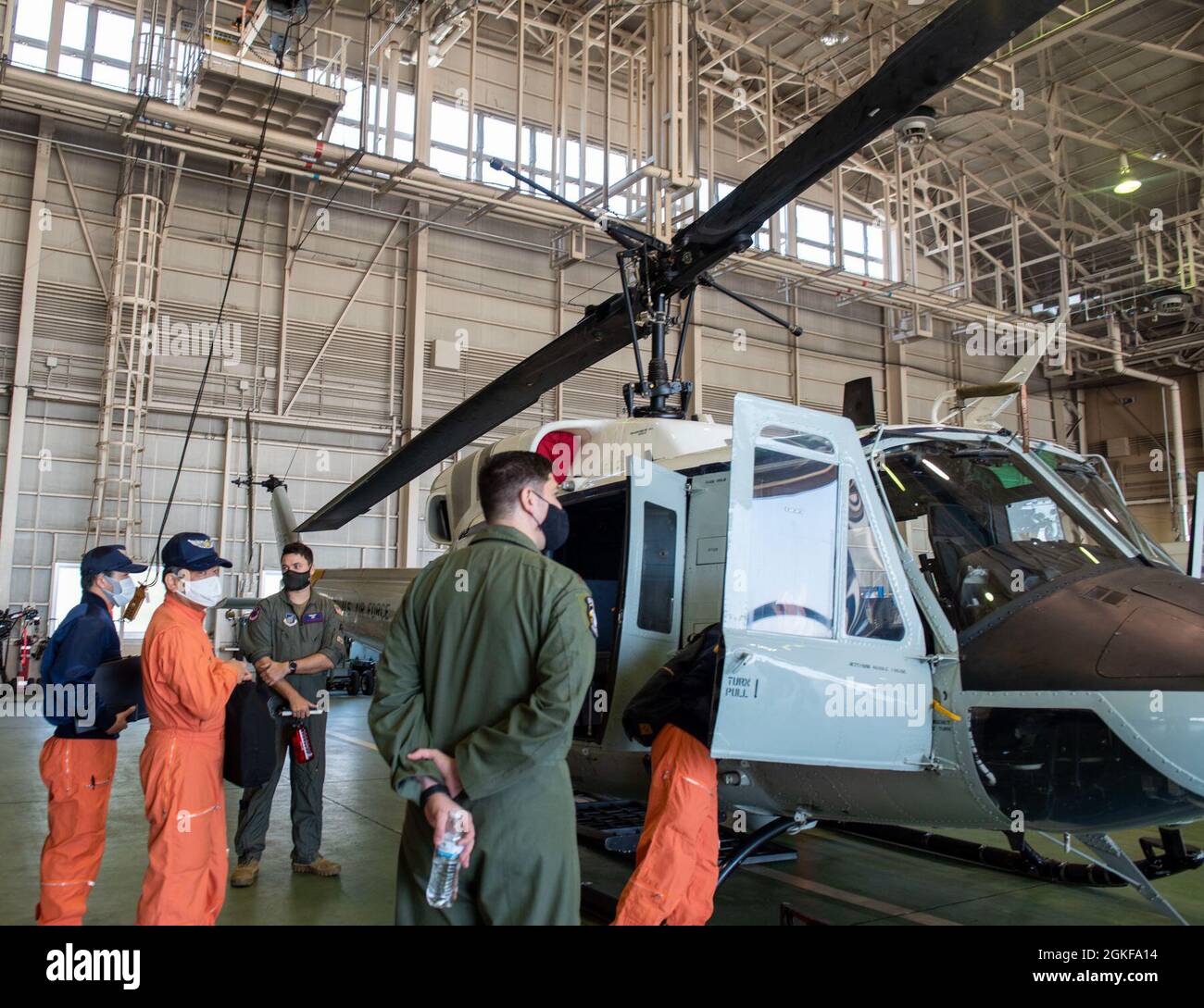 La polizia metropolitana di Tokyo e i guardiani della Costa del Giappone ispezionano un UH-1N assegnato al 459o Squadrone dell'Airlift, durante la conferenza di prevenzione della collisione di Mid-Air, 7 aprile 2021, alla base aerea di Yokota, Giappone. La conferenza ha evidenziato l'importanza della sicurezza, in quanto Tokyo dispone di uno degli spazi aerei più congestionati del mondo. Foto Stock