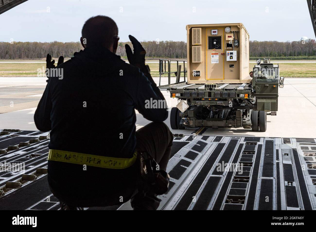 Uno specialista del servizio di rampa Aerial Port Squadron della 436a squadra marshalling un Conex surizzato negativamente su un C-17 Globemaster III sulla base dell'aeronautica di dover, Delaware, 7 aprile 2021. Il 775° volo di evacuazione Aeromedica Expeditionary ha condotto l'addestramento una volta che l'NPC è stato caricato sull'aeromobile. Foto Stock