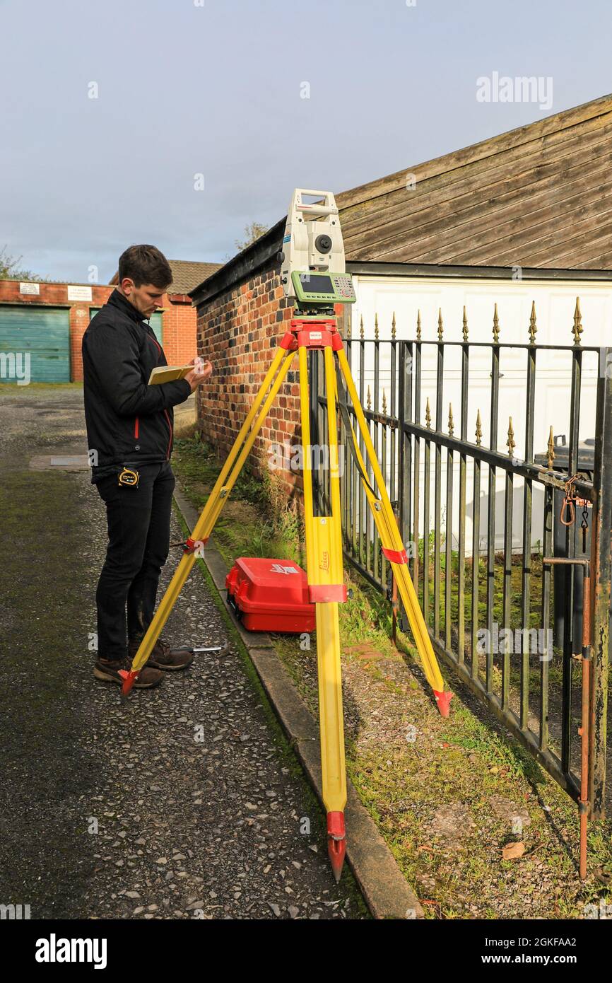 Un topografo che svolge un'indagine topografica utilizzando una stazione Leica Pinpoint R500 totale, o la stazione totale teodolite, Inghilterra, Regno Unito Foto Stock