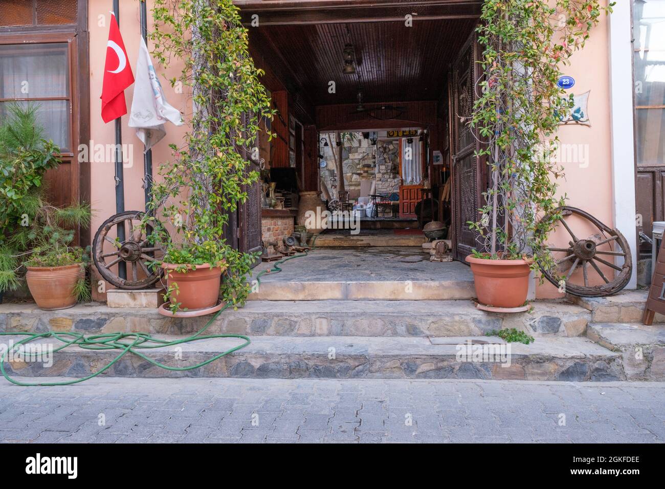 Urla, Izmir, Turchia - 03.08.2021: Piccolo ostello e ingresso hotel con un cancello storico e bandiera turca Foto Stock