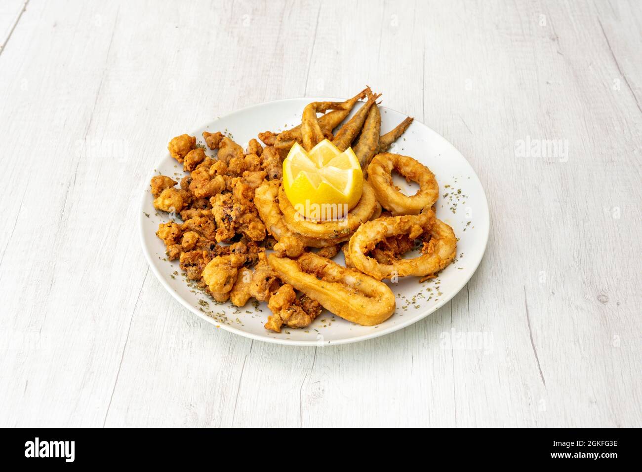 Gamberi fritti andalusi, anelli di calamari e acciughe impanate su un piatto bianco Foto Stock