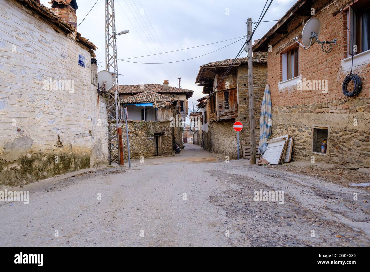 Birgi, Izmir, Turchia - 03.09.2021: Case in pietra e adobe nel villaggio di Birgi e locale strada tradizionale sotto il cielo blu con spazio copia Foto Stock