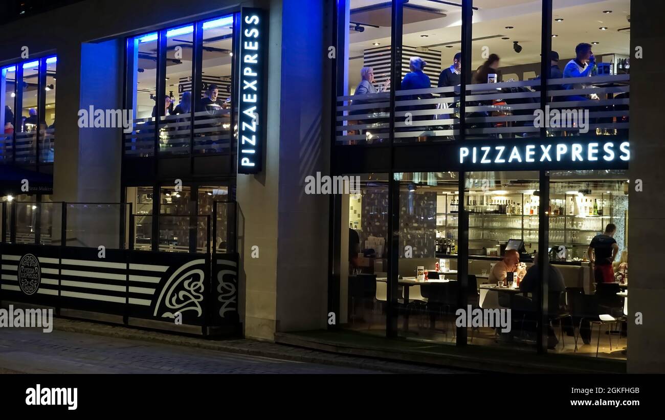 Londra, UK - 04 ottobre 2019: Ristorante Pizza Express di notte con luci e clienti visibili attraverso le finestre Foto Stock