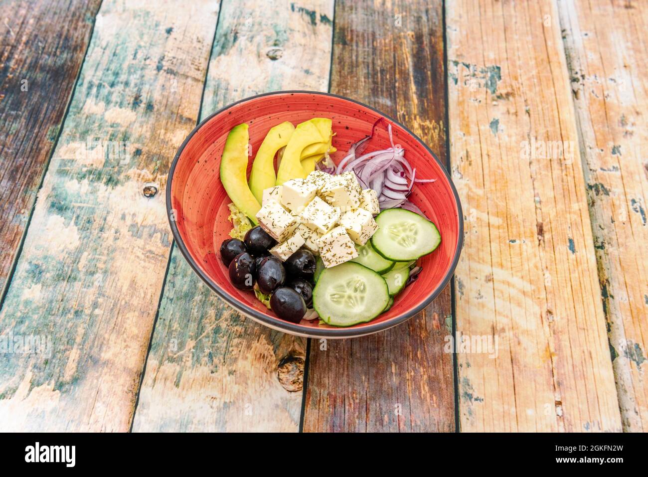 Versione insalata greca con avocado, cipolla rossa, cetrioli crudi con buccia, olive nere e feta a dadini con olio d'oliva spagnolo Foto Stock