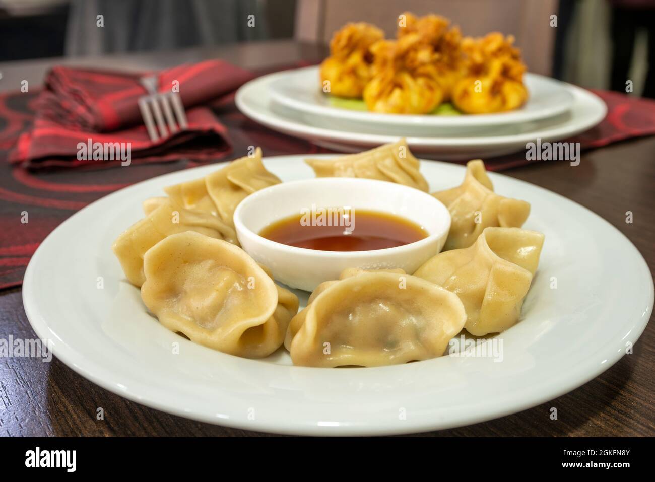 Serve gyozas al vapore guarnito con salsa di soia su un piatto bianco in un ristorante cinese Foto Stock