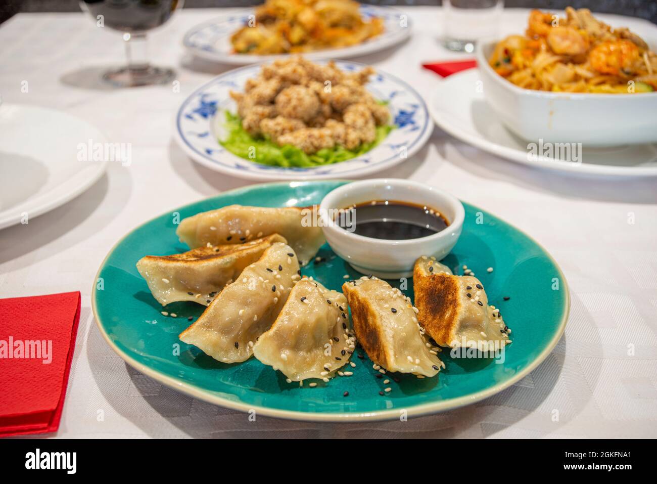 Piatto con una porzione di gyozas cucinato sul grill, dim sum, con salsa di soia, semi di papavero e sesamo su un piatto blu di un ristorante cinese Foto Stock