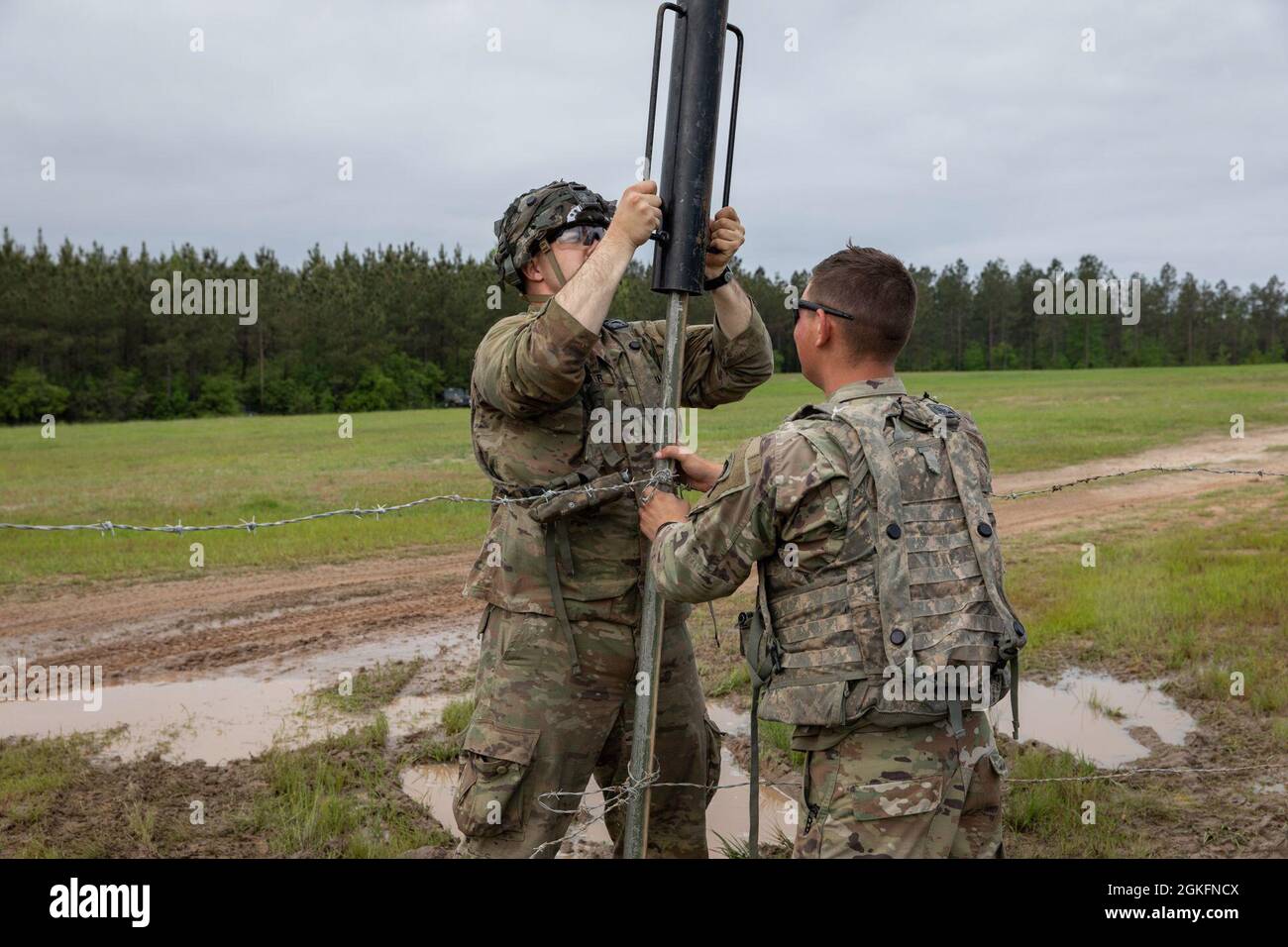 Esercito degli Stati Uniti Pvt. Prima classe Byron Mortimer, a sinistra, un uomo di fanteria assegnato alla sede centrale e sede centrale della brigata, e SPC. Justin Yost, Right, un ingegnere di combattimento assegnato alla sede centrale e alla sede centrale, 317th Brigade Engineer Battaglione, 3rd Brigade Combat Team, 10th Mountain Division, ha messo a terra pali metallici mentre ha messo a filo spinato intorno al perimetro dell'area delle operazioni tattiche delle brigate presso il Joint Readiness Training Center Rotation 21-06, A Fort Polk, Louisiana, 10 aprile 2021. Il filo spinato e il filo a soffietto aggiungono un ulteriore strato di sicurezza fisica durante il lavoro sul campo Foto Stock