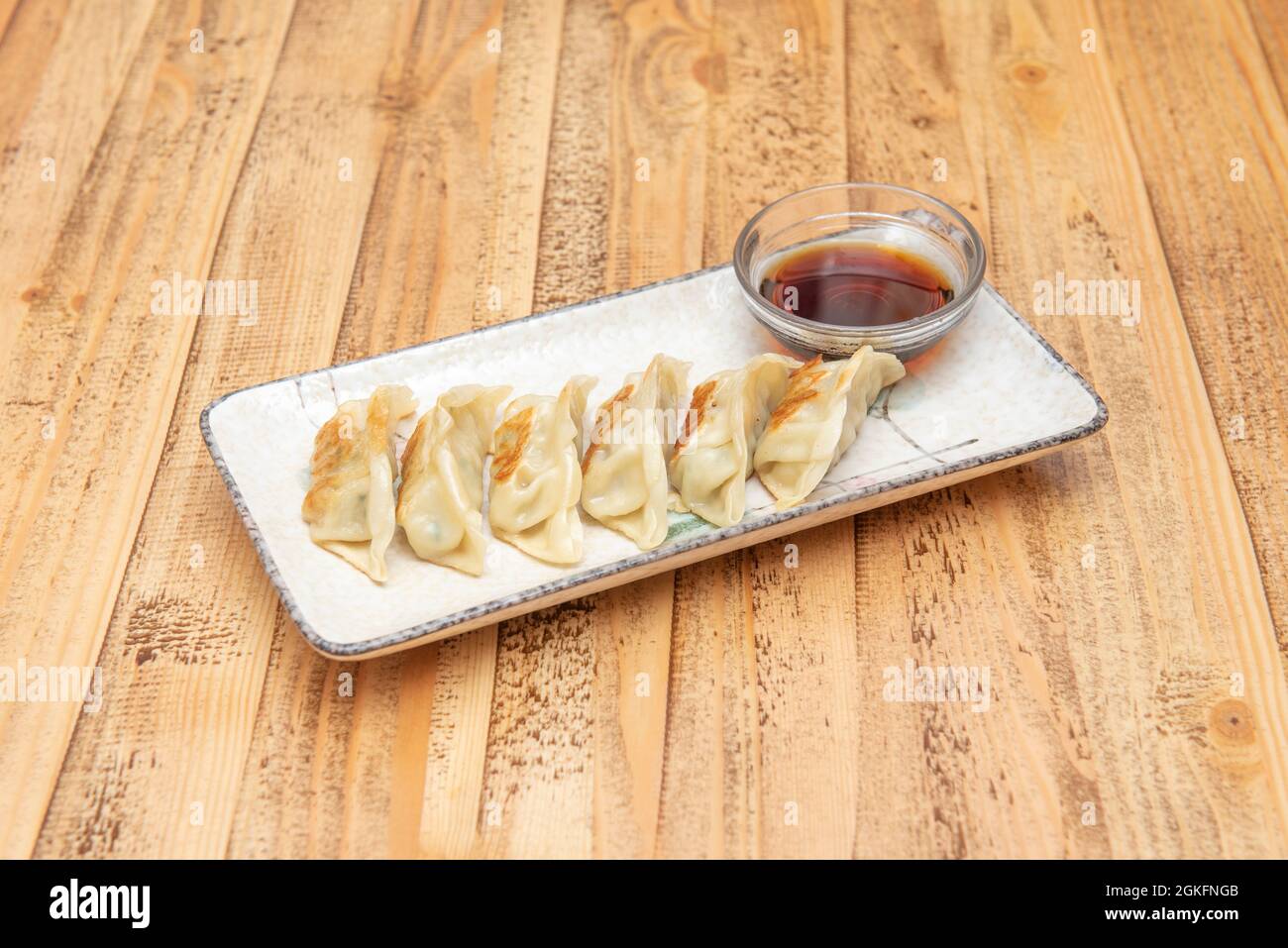 Piatto popolare di gnocchi asiatici fritti gyozas alla griglia con salsa di soia per immergersi su un bellissimo piatto bianco Foto Stock