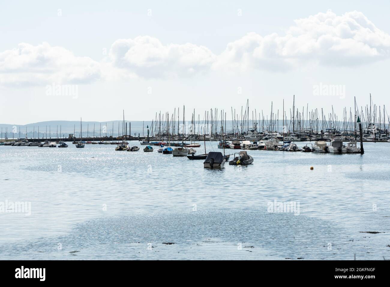 Barche ormeggiate a Lymington, a Hants con l'isola di Wight nel terreno posteriore Foto Stock