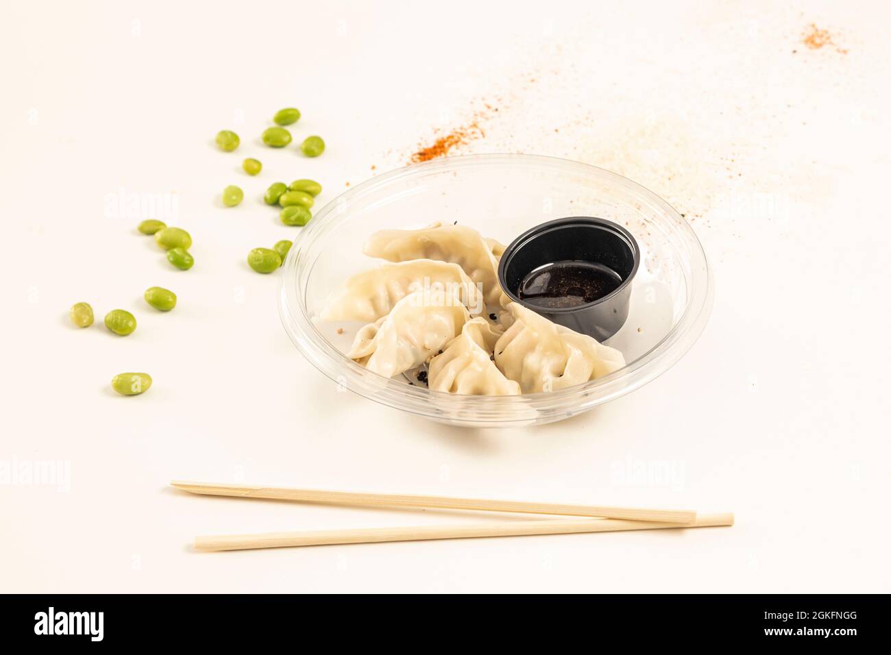 Gnocchi giapponesi ripieni di gamberi, gyozas, al vapore e posti all'interno di un piatto trasparente con bacchette in primo piano Foto Stock