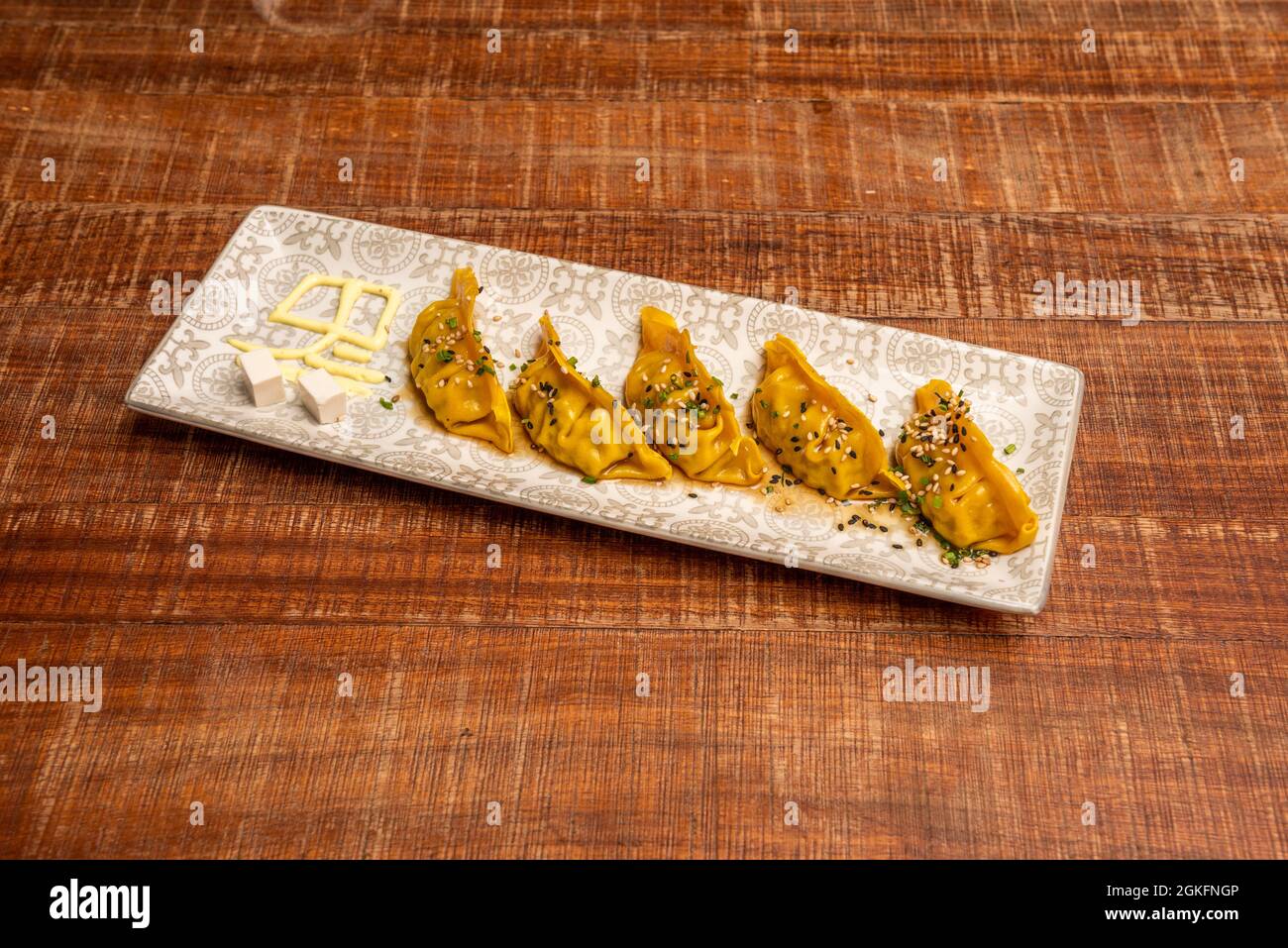 Gnocchi giapponesi al vapore con ricetta al curry giallo con erba cipollina e semi di papavero e vassoio grigio sesamo Foto Stock