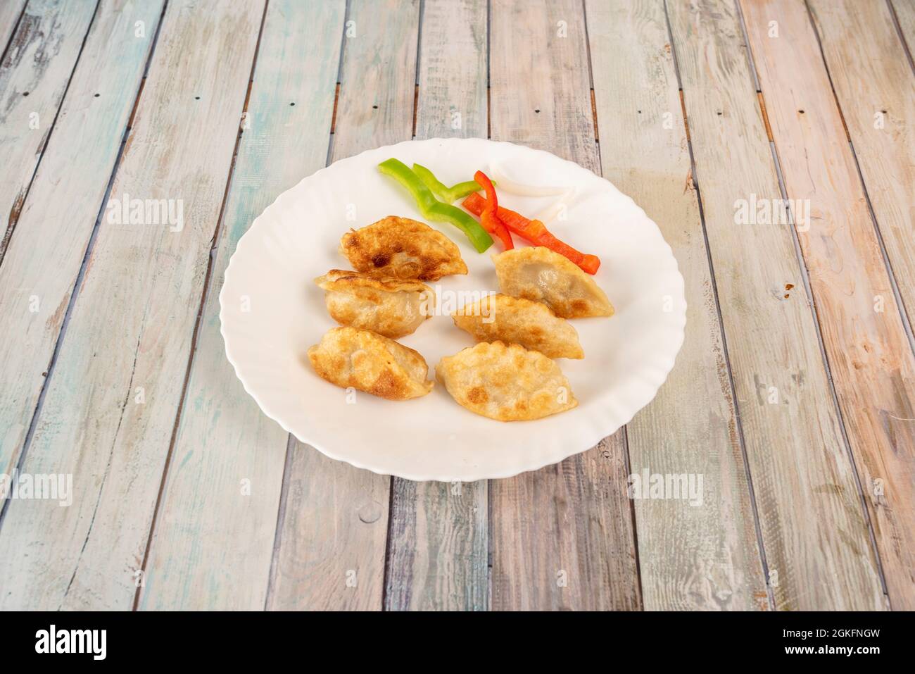 Gnocchi cinesi fritti gyozas farciti con verdure su piatto bianco rotondo Foto Stock