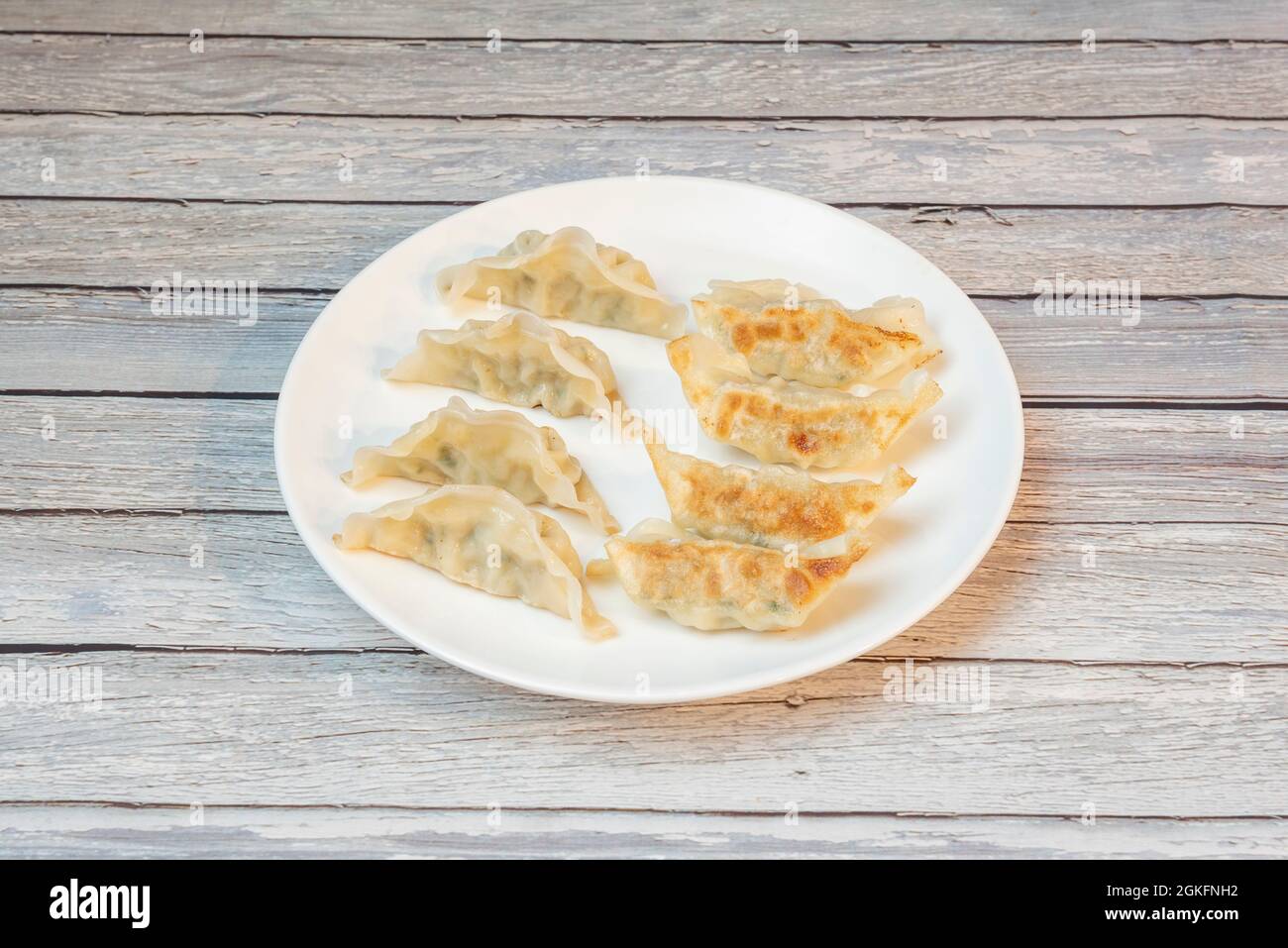 Piatto di gnocchi cinesi fritti alla griglia su piatto bianco rotondo Foto Stock
