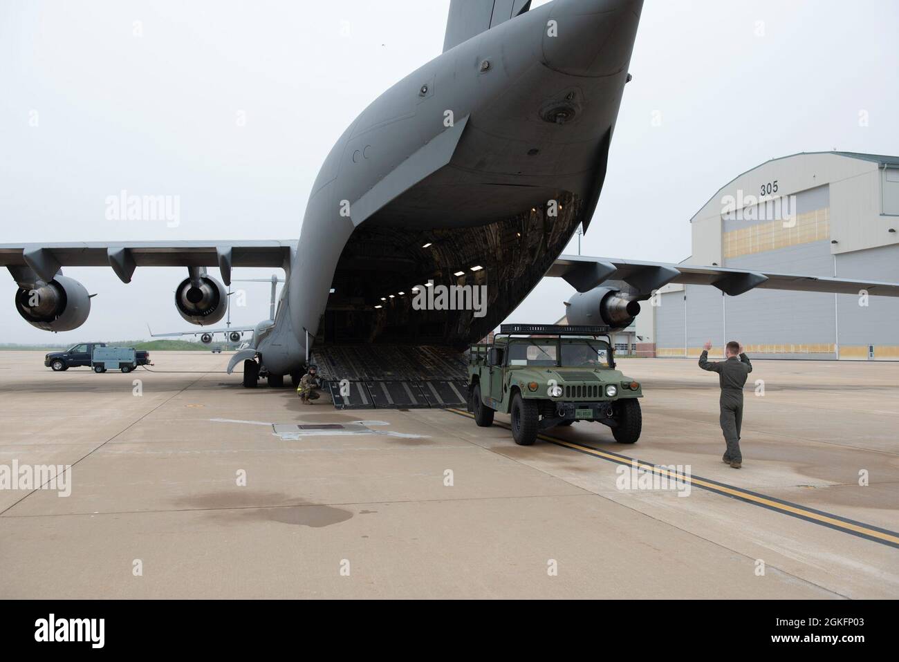 US Air Force Airman 1st Class Peter Dunn, un loadmaster con il 167th Operations Support Group aiuta a guidare un veicolo ad alta mobilità su un aereo C-17 Globemaster III durante un esercizio di addestramento di carico di velivolo, Martinsburg, West Virginia Shepherd Field, 10 aprile 2021. È stata utilizzata una particolare cautela quando si guidano attrezzature pesanti all'interno dell'aereo per garantire la sicurezza e la prevenzione dei danni. Foto Stock