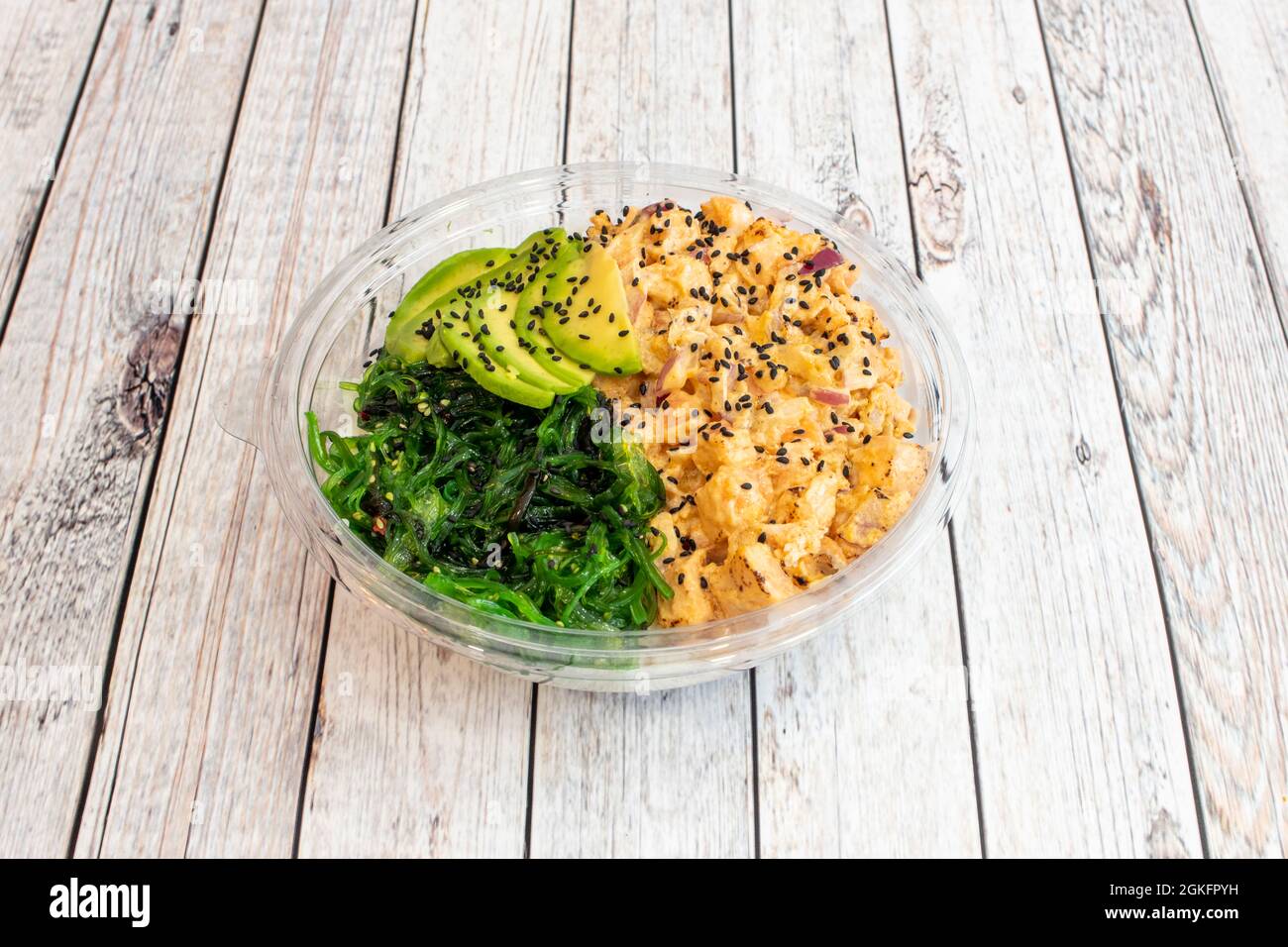 Ciotola di poke di salmone flambé con cipolla viola e semi di papavero, insalata di alghe di wakame con fette di avocado maturo Foto Stock