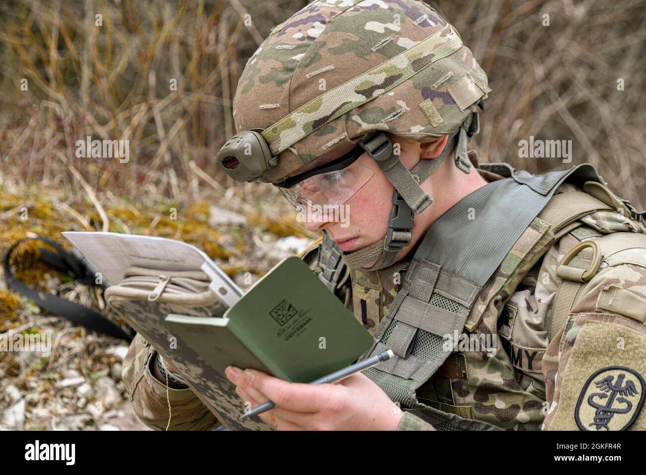 Paige Runco, assegnato al Landstuhl Regional Medical Center, si occupa delle coordinate durante il concorso MEDDAC Bavaria Best Warrior Competition presso la Grafenwoehr Training Area, Germania, 11 aprile 2021. I concorrenti sono stati testati per agilità, giudizio maturo, idoneità fisica, abilità di guerriero, navigazione terrestre e conoscenza generale delle competenze mediche, tecniche e tattiche attraverso una serie di attività pratiche in un ambiente operativo simulato. Foto Stock