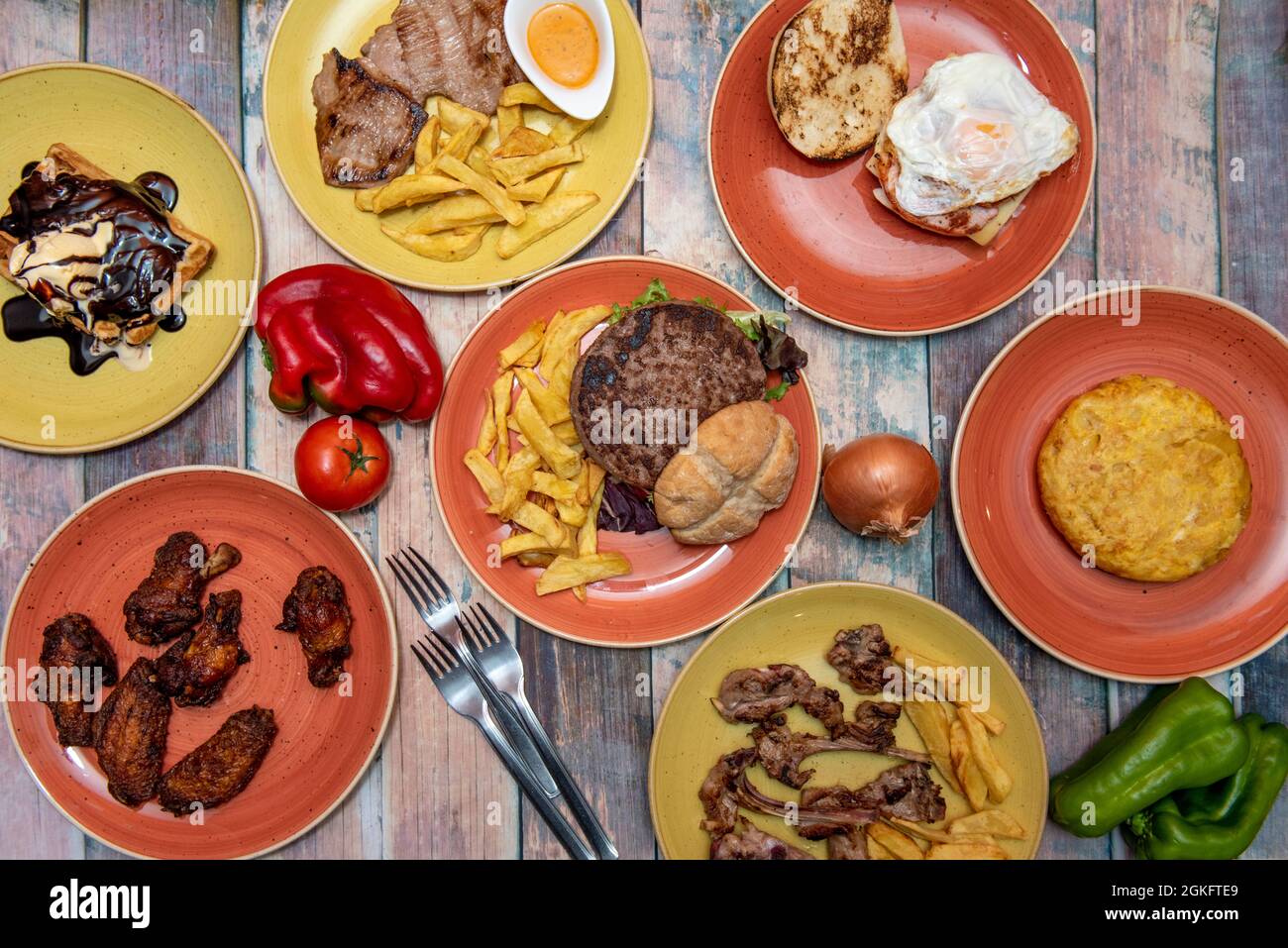 Set di piatti tradizionali spagnoli. Costolette di agnello, frittata di patate, filetto di manzo con patatine fritte fatte in casa, waffle con gelato alla vaniglia, hamburger xl Foto Stock