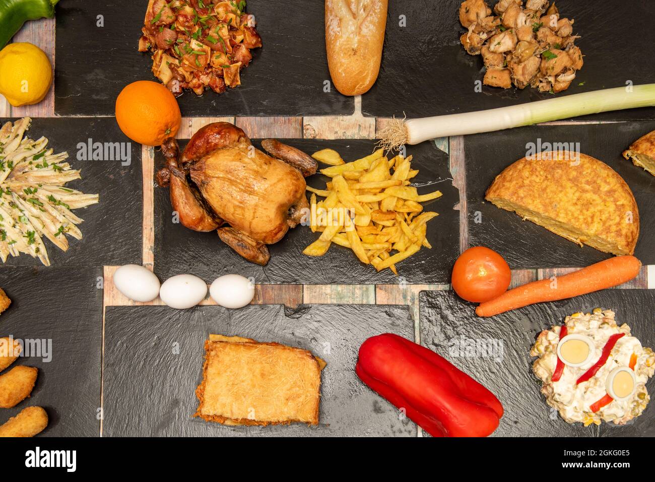 Set di piatti e tapas di cucina spagnola. Insalata russa con uova sode, pollo arrosto con patatine fritte, mezza frittata di patate, lembo fisso all'orecchio, aglio Foto Stock