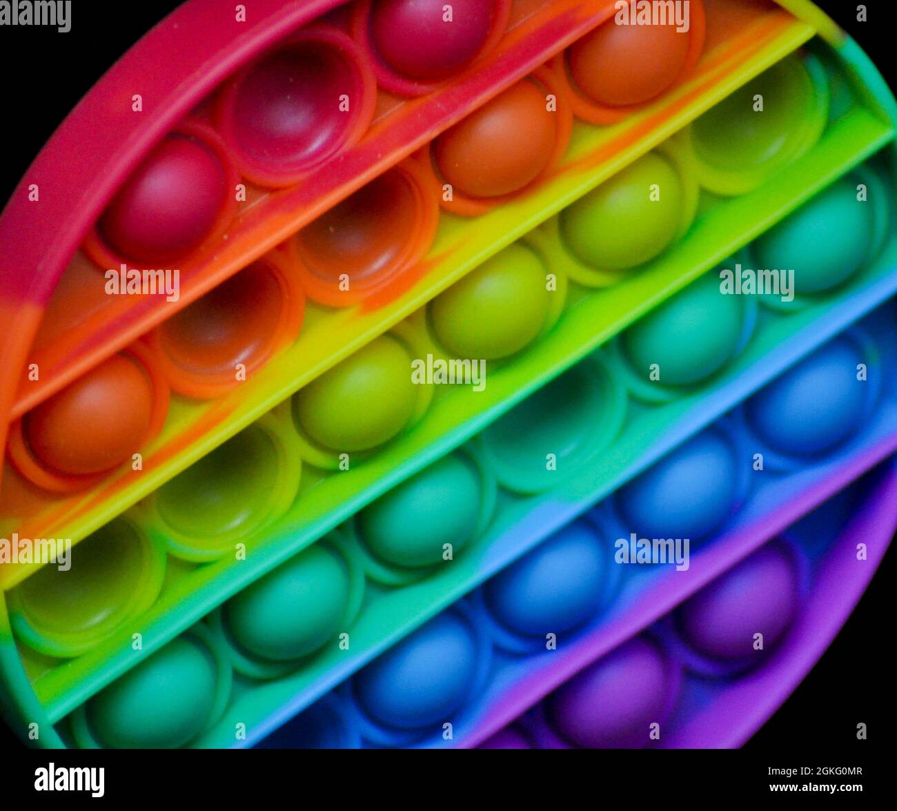 Giocattolo di popper di fedget color arcobaleno per aiutare ad alleviare l'ansia o le difficoltà sensoriali nei bambini. L'immagine viene impostata su uno sfondo nero Foto Stock