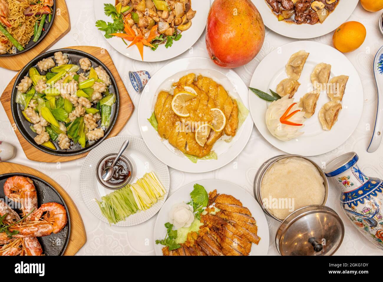 Immagine vista dall'alto dei piatti cinesi. Pollo al limone, anatra alla zucca, pasta di riso cinese, gyozas farciti, mango e gamberi alla griglia Foto Stock