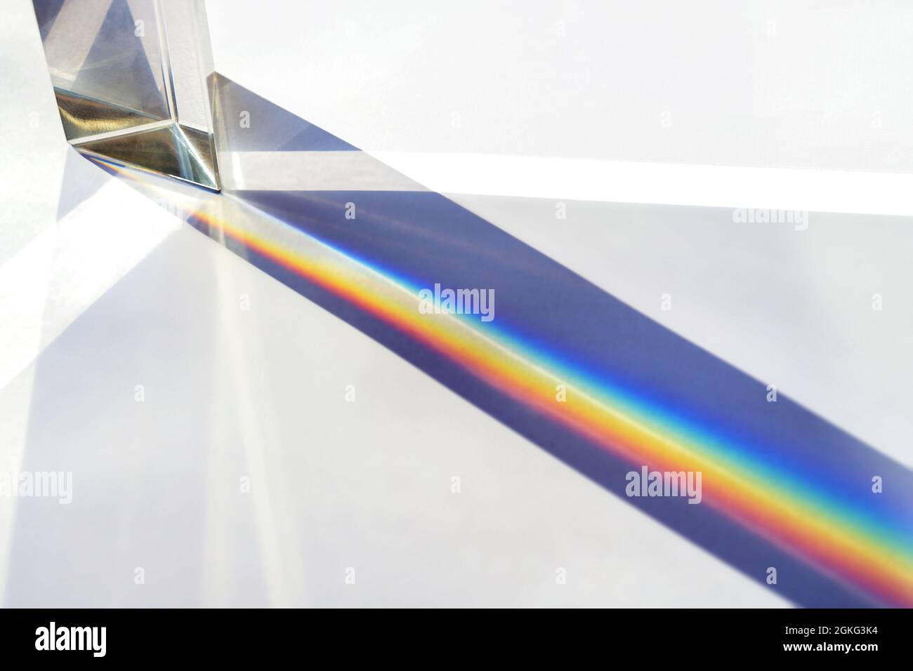 Prisma di vetro per esperimenti di fisica ottica in educazione, dividendo la luce in fasci di riflessione nello spettro dei colori arcobaleno, backgrou luminoso Foto Stock