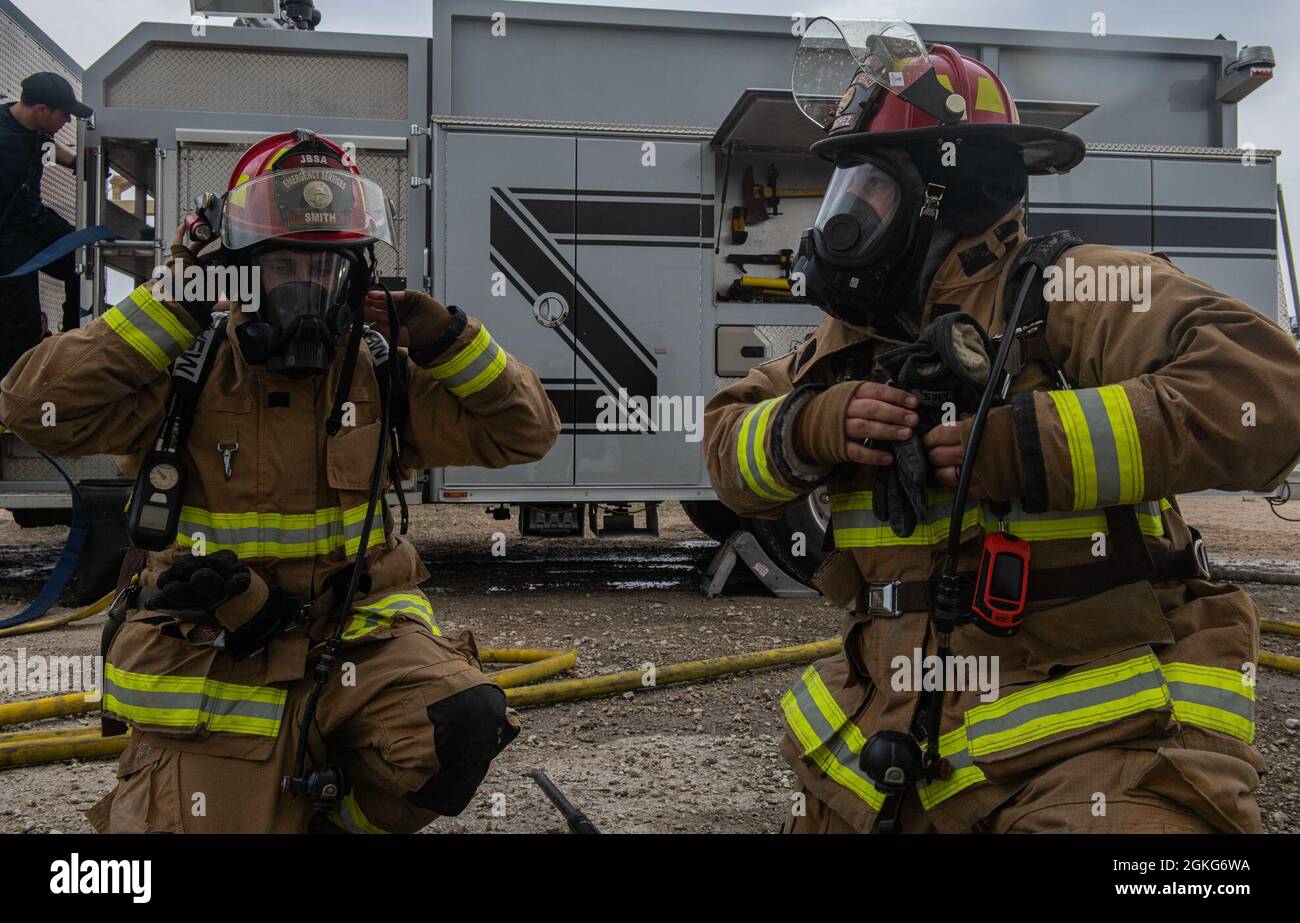 Forza aerea degli Stati Uniti Sgt. David Smith, a sinistra, e Andrew Sanchez, a destra, Joint base San Antonio 902nd Ingegnere civile Squadron guida i vigili del fuoco, si preparano per uno scenario di ingresso forzato durante un esercizio di addestramento al fuoco dal vivo, 14 aprile 2021, presso la Joint base San Antonio-Randolph, Texas. I partecipanti alla formazione si sono svolti attraverso vari esercizi di fuoco dal vivo e hanno praticato risposte diverse a ciascun esercizio. Foto Stock