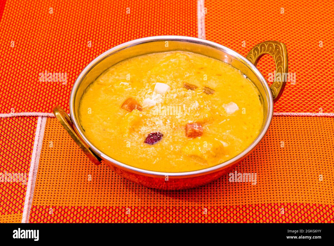 Curry di pollo, korma, servito in una tradizionale ciotola di metallo indù su tovaglie d'arancia Foto Stock