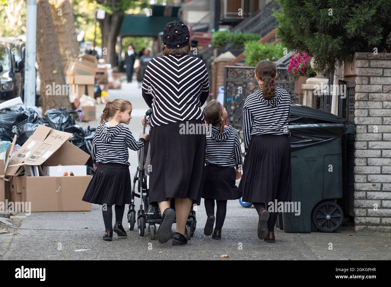 Una madre hasidica e 3 figlie, tutte vestite modestamente e in modo molto simile in bianco e nero. Su una strada a Williamsburg, Brooklyn, New York City Foto Stock