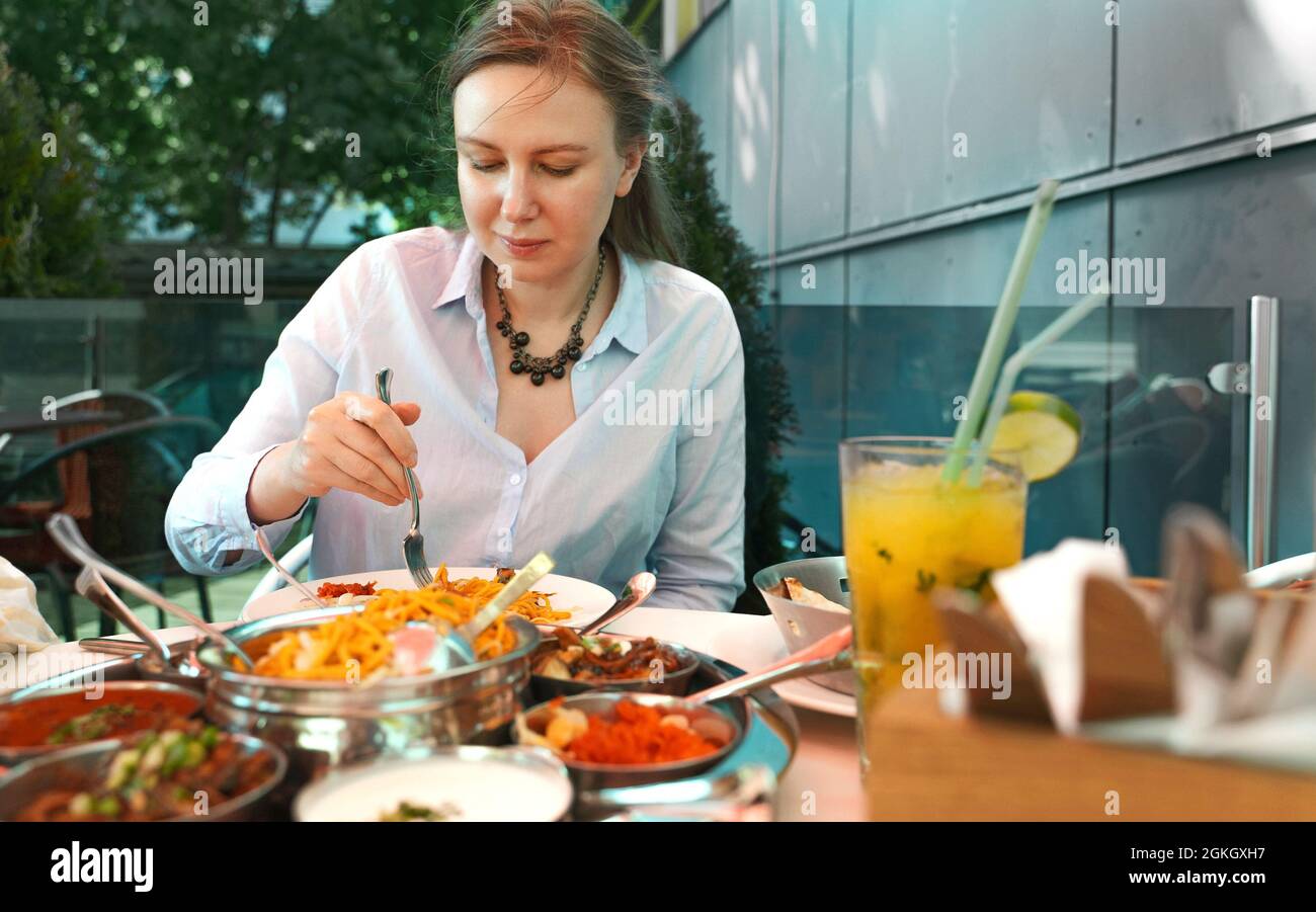 La donna sta mangiando cibo indiano in un ristorante. Foto Stock
