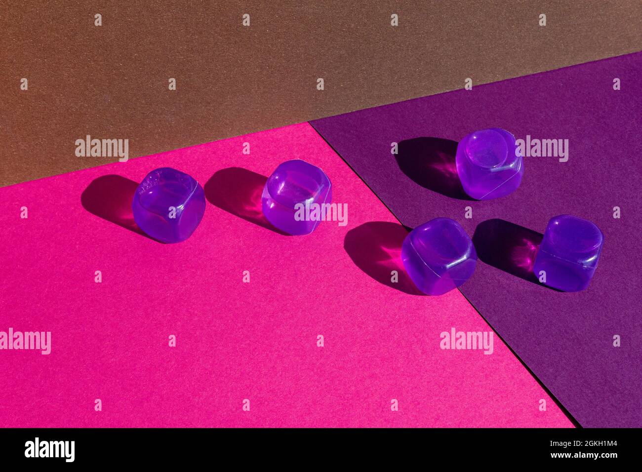 Layout creativo con colorati cubetti di ghiaccio in plastica al sole di mezzogiorno e ombre dure sullo sfondo. Estate mockup. Disposizione piatta. Foto Stock