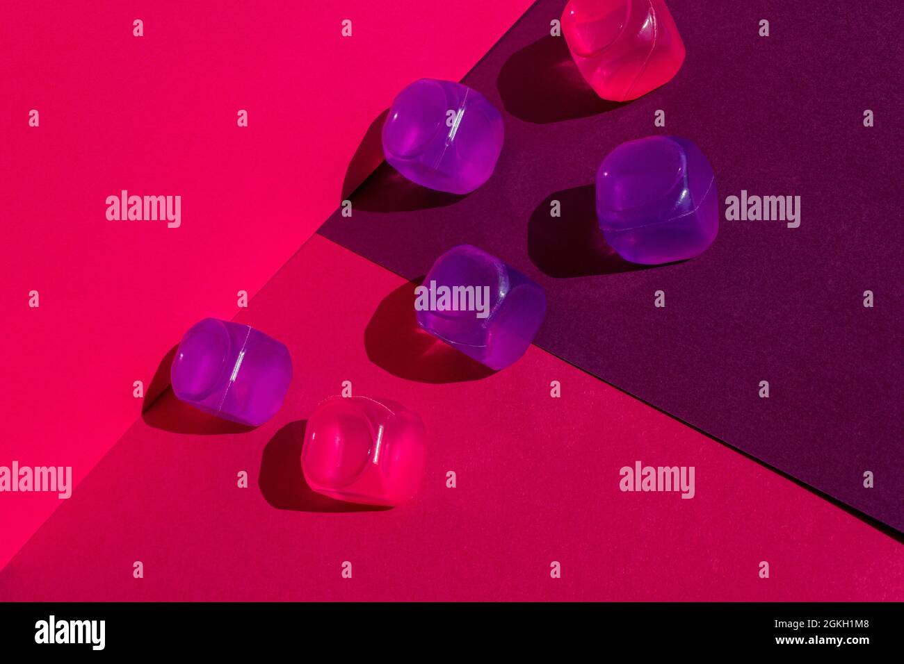 Layout creativo con colorati cubetti di ghiaccio in plastica al sole di mezzogiorno e ombre dure sullo sfondo. Estate mockup. Disposizione piatta. Foto Stock