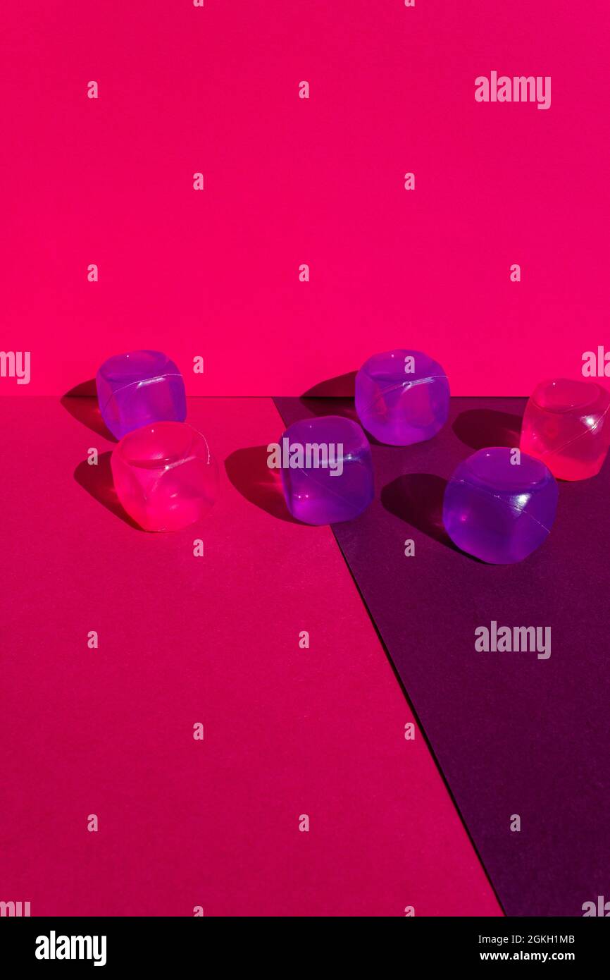 Layout creativo con colorati cubetti di ghiaccio in plastica al sole di mezzogiorno e ombre dure sullo sfondo. Estate mockup. Foto verticale. Foto Stock