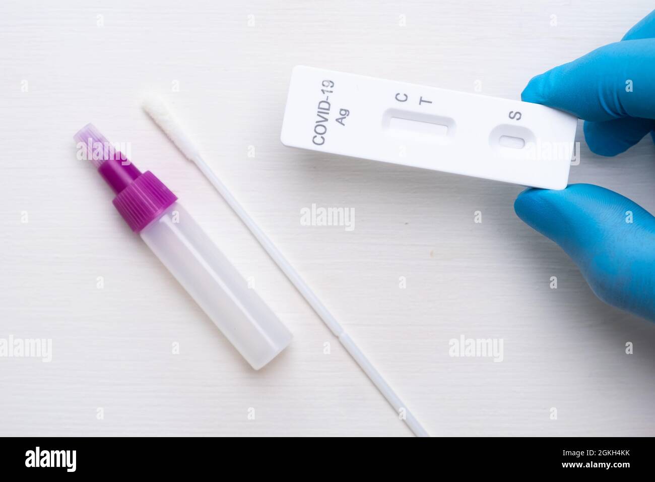 Nuovo test antigenico per coronavirus e kit per diagnostica rapida in mano medica con guanti di gomma su sfondo bianco Foto Stock