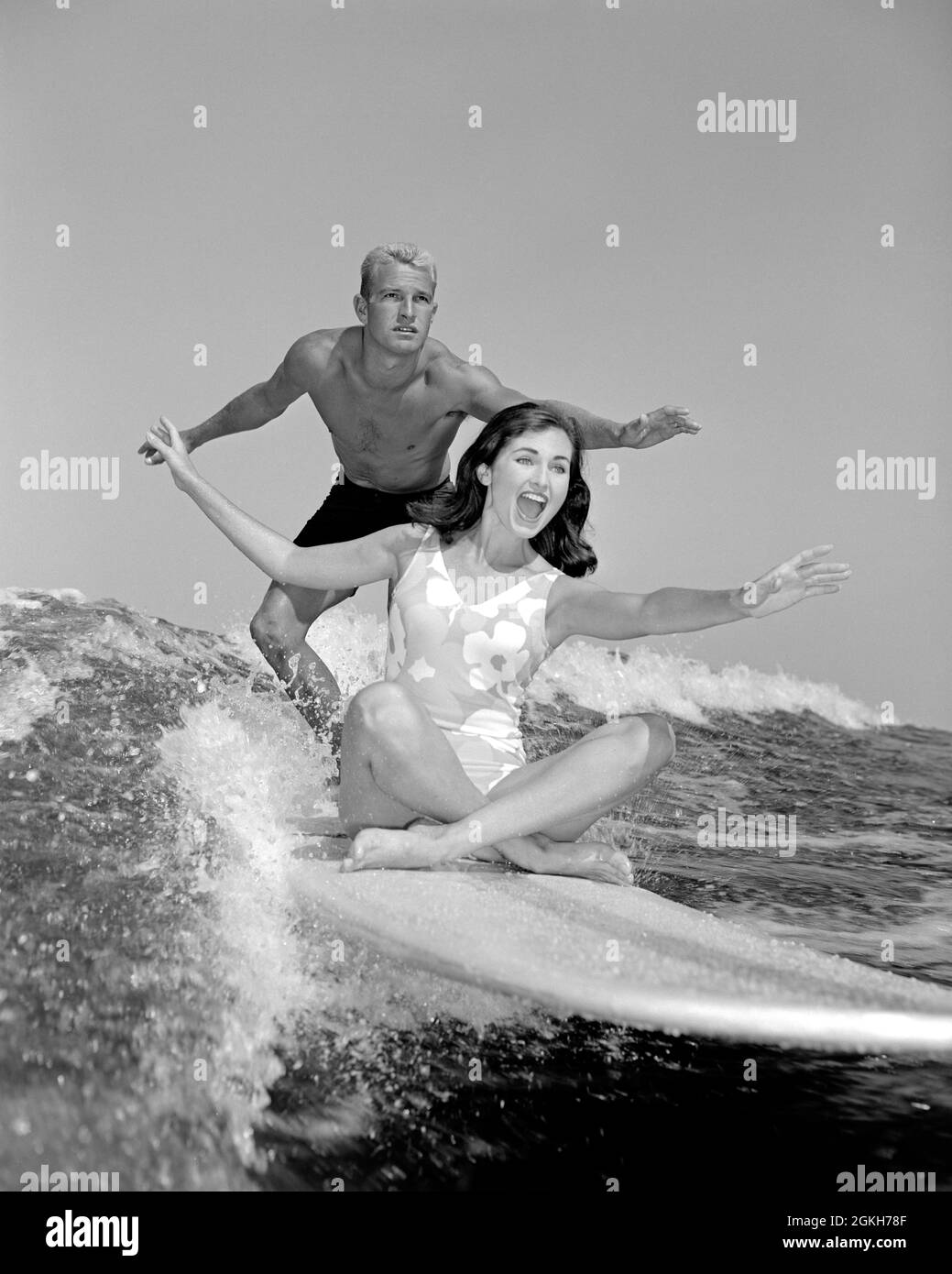 1960S COPPIA ANONIMA RIDENDO DONNA SEDUTA SU TAVOLA DA SURF CON UOMO IN PIEDI BRACCIA FUORI PER EQUILIBRIO CERCANDO SERIO - A7692 CYP001 HARS VECCHIO MODO 1 FITNESS RIDERE SANO GIOVANE ADULTO EQUILIBRIO LAVORO DI SQUADRA SURF ONDE ATLETA FELICE GIOIA LIFESTYLE VELOCITÀ FEMMINE SPOSATE CONIUGE MARITI CRESCERE ATLETICA COPIA SPAZIO AMICIZIA FULL-LENGTH SIGNORE FISICO FITNESS PERSONE ADULTI MASCHI ADOLESCENTI RAGAZZA ADOLESCENTE RAGAZZO ATLETICA COPPIE SURF B&W UOMINI E DONNE PARTNER ABILITÀ ATTIVITÀ FISICA BRIVIDO RAFFORZAMENTO PERDITA DI PESO ALLEGRO AVVENTURA FORZA AUTOSTIMA ECCITAZIONE BASSO ANGLE RICREAZIONE RAPPORTI SORRIDE Foto Stock