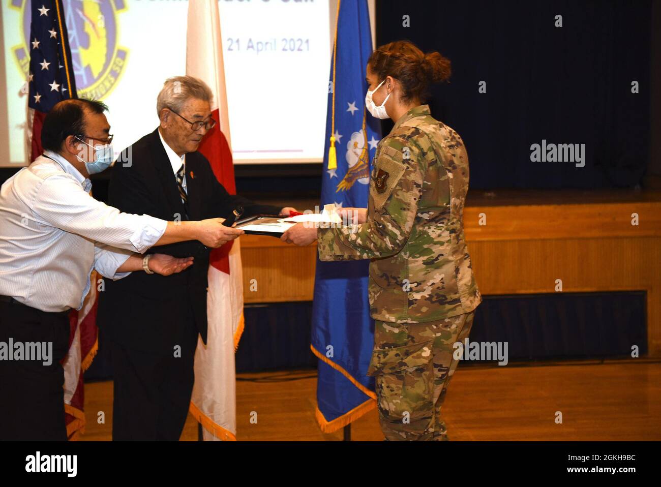 Città di Misawa Social Welfare Vice Presidente, Ishi Numata, premia US Air Force Senior Airman Hannah Tatum, 35esimo tecnico dei sistemi di trasmissione a radiofrequenza Squadron di comunicazione, una lettera di apprezzamento durante una chiamata generale alla base aerea di Misawa, 21 aprile 2021. Tatum ha ricevuto la lettera per il suo duro lavoro di volontariato nei programmi post-scolastici giapponesi, chiamati “Jido-kan”, rendendola più divertente per tutti. Foto Stock
