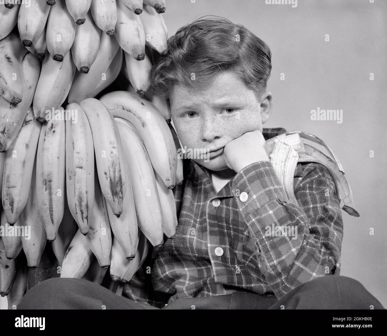 1930 ANNI 1940 STRESSATO RECKLE AFFRONTATO RAGAZZO CON MAL DI STOMACO GUARDANDO LA MACCHINA FOTOGRAFICA SEDUTA DA UN MAZZO DI BANANE UNA METÀ MANGIATO IN HAND - J53 HAR001 HARS RISCHIO DISTURBATO B&W INTERESSATO TRISTEZZA CONTATTO CON GLI OCCHI TENTAZIONE HUMOROUS BENESSERE STOMACO SCELTA REDHEAD GIUDIZIO COMICO UMORE ROSSO CAPELLI CONCETTUALE GLUM COMMEDIA GIOVANI MISERABILE PRE-TEEN RAGAZZO NERO E BIANCO ETNIA CAUCASICA HAR001 VECCHIO STILE Foto Stock