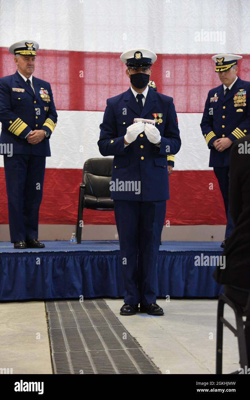 Membro della Cutter della Guardia Costiera Douglas Munro (WHEC 724) presenta un pennant durante la cerimonia di smantellamento dei tagliatori a Kodiak, Alaska, 24 aprile 2021. La taglierina a base di Kodiak è l'ultima delle tagliatrici di classe di resistenza alta 378 piedi, che ha servito la Guardia Costiera conducendo missioni nazionali e internazionali per 49 anni. Foto Stock