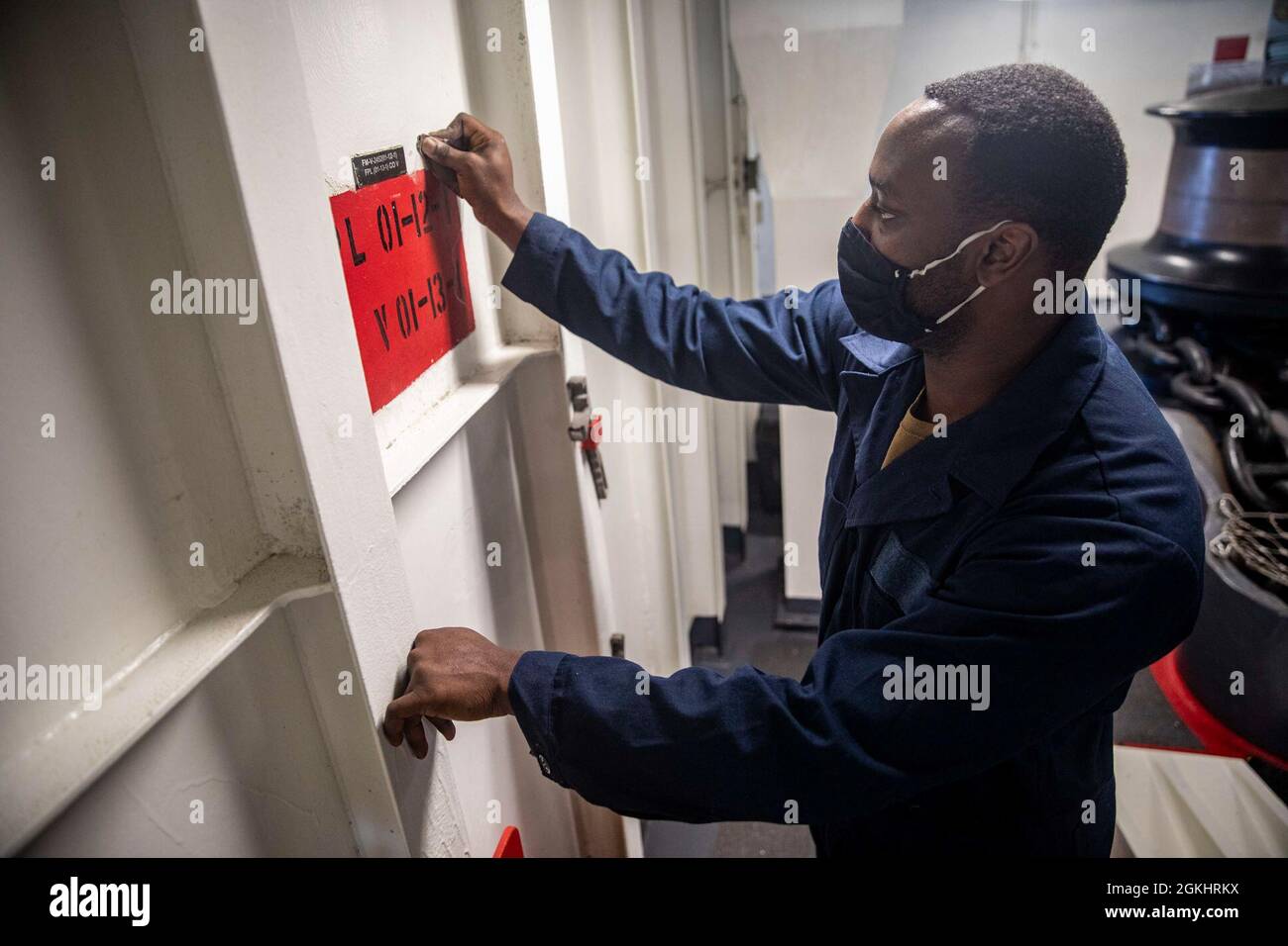 OCEANO PACIFICO (27 aprile 2021) – il Mate Seaman Frank Bowman della Marina degli Stati Uniti di Boatswain sabbia una paratia in preparazione alla pittura a bordo della nave d'assalto anfibio USS Makin Island (LHD 8). Il Makin Island Amphibious Ready Group e la 15th Marine Expeditionary Unit stanno operando nell'area della 7th Fleet statunitense come parte di un dispiegamento programmato nella regione. Come la più grande flotta della Marina degli Stati Uniti, la settima flotta opera e interagisce regolarmente con 35 nazioni marittime, conducendo missioni per preservare e proteggere una regione indopacifica libera e aperta. Foto Stock