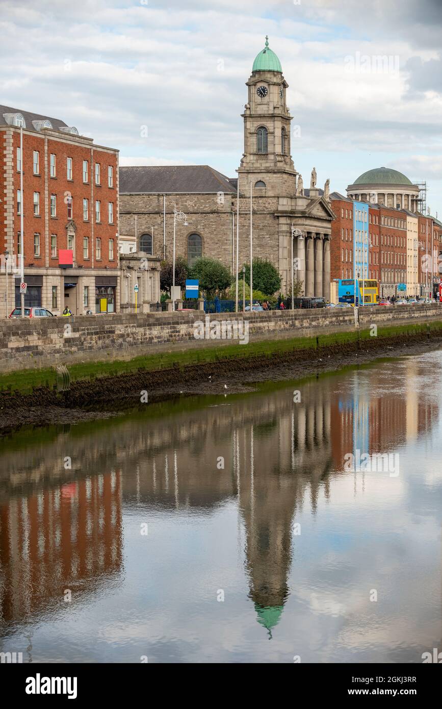 Chiesa di San Paolo e riflessione nelle acque del fiume Liffey come passa attraverso il centro di Dublino in una giornata nuvolosa senza pioggia Foto Stock