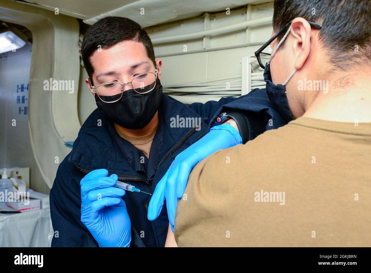 OCEANO PACIFICO (30 aprile 2021) – il Corpsman 3° Classe Adriel Arredondo, di Dallas, a sinistra, amministra un vaccino COVID-19 al Mate Fireman Joseph Brooks di Jasper, GA., a bordo della portaerei USS Theodore Roosevelt (CVN 71) il 30 aprile 2021. Il gruppo Theodore Roosevelt Carrier Strike è in fase di implementazione programmata che conduce operazioni di routine nella terza flotta statunitense. Foto Stock