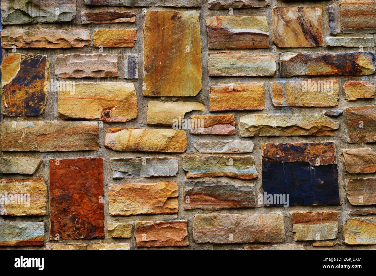 Il muro esterno di un liceo costruito da varie pietre, mattoni e rocce Foto Stock