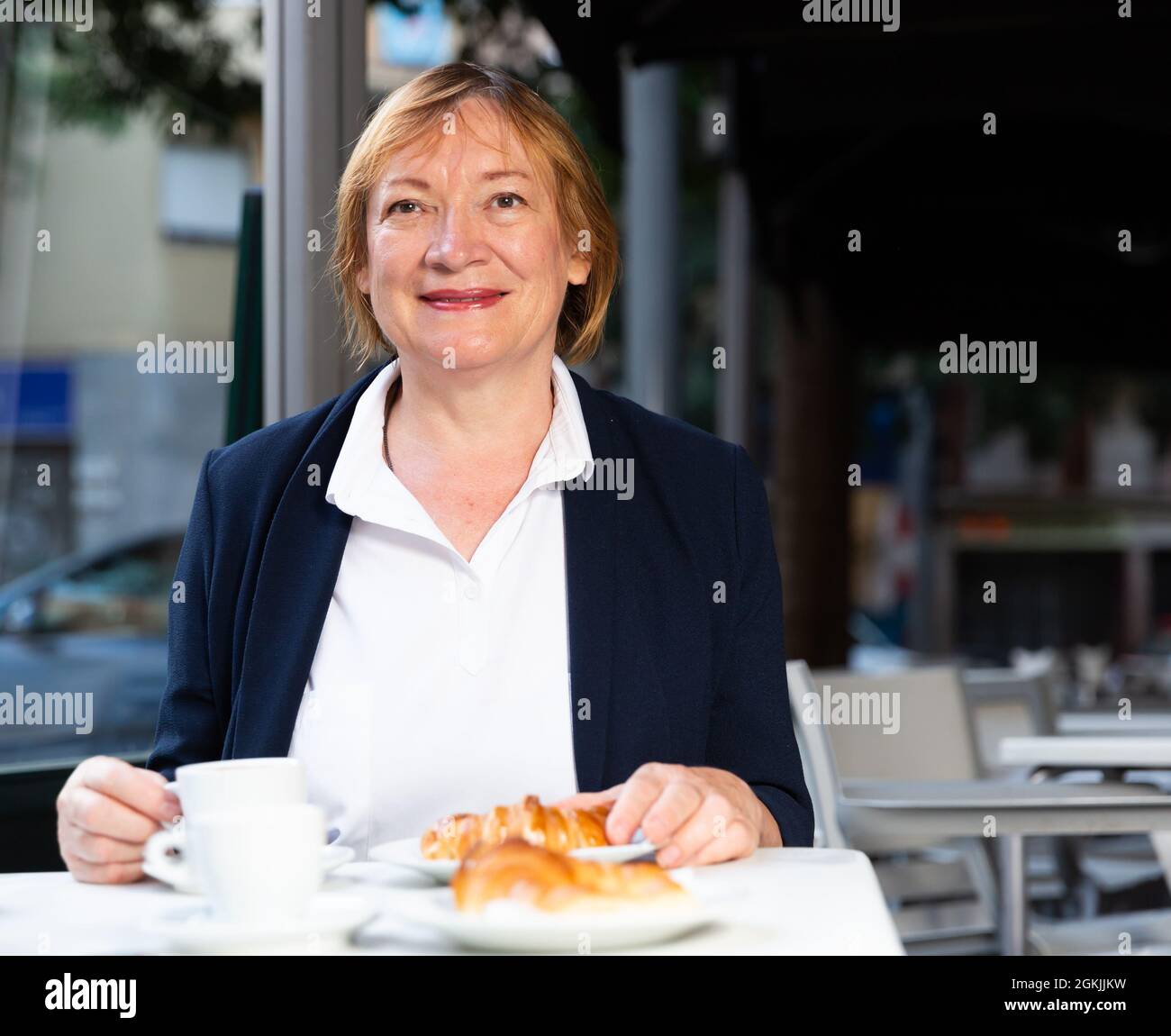 Donna anziana che fa colazione in caffetteria Foto Stock