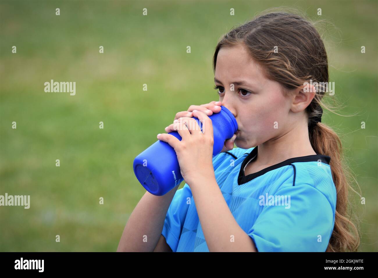ragazza di 9 anni a metà tempo della sua prima partita di calcio mai bevendo liquido e indicando la squadra avversaria che hanno perso per copiare il testo dello spazio Foto Stock