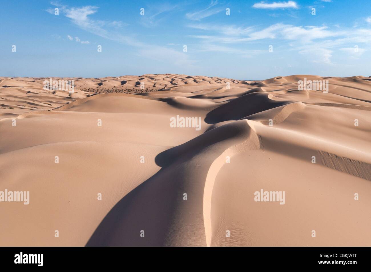 Grandi dune di sabbia con texture, motivi, luce e ombra. Cielo blu con nuvole bianche Foto Stock