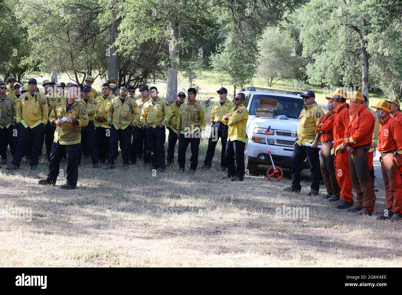 California National Guardsmen, in giallo, con Joint Task Force Rattlesnake - Fresno Unit, ascoltare un consiglio di sicurezza del Dipartimento della foreste e della protezione antincendio della California (CAL FIRE) accanto ai detenuti con il Dipartimento delle correzioni e della riabilitazione della California (DEPCOR) 12 maggio 2021 presso il sito di formazione CAL FIRE Millerton a Friant, California. I team CAL Guard e DEPCOR hanno subito valutazioni per essere certificati come equipaggi antincendio per attacchi iniziali di tipo II. Foto Stock