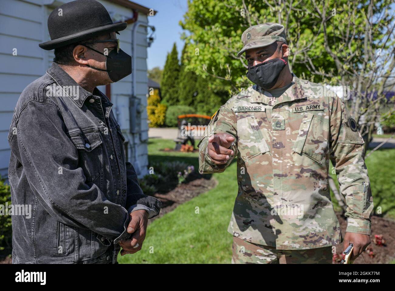 Esercito degli Stati Uniti Sgt. 1st Class Victor Gardner, a destra, un ufficiale non commissionato di Washington D.C. nativo e operazioni di affari pubblici assegnato al 5th Mobile Public Affairs distaccamento di stanza alla base congiunta Lewis-McChord, Washington, parla con Tito Jackson nella casa della famiglia Jackson di fronte alla strada dallo stato-guidato, Gary Community Vaccine Center, sostenuto a livello federale, presso l'ex Roosevelt High School di Gary, Indiana, 13 maggio 2021. Gardner, che è un grande fan della famiglia Jackson, ha partecipato ad un annuncio di servizio pubblico con i fratelli Jackson, Marlon e Tito, per garner suppor Foto Stock